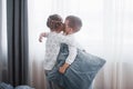 Happy kids playing in white bedroom. Little boy and girl, brother and sister play on the bed wearing pajamas. Nightwear Royalty Free Stock Photo