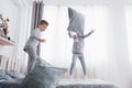 Happy kids playing in white bedroom. Little boy and girl, brother and sister play on the bed wearing pajamas. Nightwear Royalty Free Stock Photo