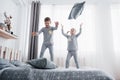 Happy kids playing in white bedroom. Little boy and girl, brother and sister play on the bed wearing pajamas. Nightwear Royalty Free Stock Photo