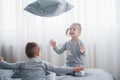 Happy kids playing in white bedroom. Little boy and girl, brother and sister play on the bed wearing pajamas. Nightwear Royalty Free Stock Photo