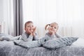 Happy kids playing in white bedroom. Little boy and girl, brother and sister play on the bed wearing pajamas. Nursery Royalty Free Stock Photo