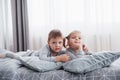 Happy kids playing in white bedroom. Little boy and girl, brother and sister play on the bed wearing pajamas. Nursery Royalty Free Stock Photo