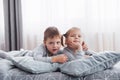 Happy kids playing in white bedroom. Little boy and girl, brother and sister play on the bed wearing pajamas. Nursery Royalty Free Stock Photo