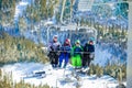 Happy kids sit on ski chairlift over winter forest Royalty Free Stock Photo