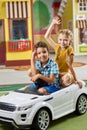 Happy kids sitting in toy car and looking at camera. Royalty Free Stock Photo