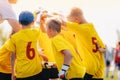 Happy kids soccer team huddling and stacking hand together before game