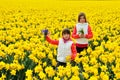 Happy kids with spring flowers on yellow daffodils field, children on vacation in Netherlands