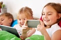 Happy kids with tablet pc and and smartphone in bed Royalty Free Stock Photo