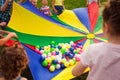 Happy kids waving rainbow parachute full of balls Royalty Free Stock Photo