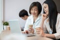 A happy and kind senior Asian businesswoman is working with a young female colleague in the office