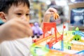 Happy kindergarten kid boy playing with rail road toy game,asian little child having fun enjoy with toys car in nursery, Royalty Free Stock Photo