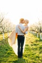Happy kissing wedding couple in love in beautiful blooming garden in spring sunny day, man holding woman on hands Royalty Free Stock Photo