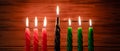 Happy Kwanzaa. African American holiday. Seven burning candles, red, black and green, in kinara candlestick. Royalty Free Stock Photo