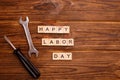 Happy Labor Day greeting card concept. HAPPY LABOR DAY wooden text with tools on wooden background. Flat lay, top view. Royalty Free Stock Photo