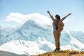 Happy lady hiker stands with raised arms against mountains Royalty Free Stock Photo