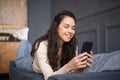 Happy lady lying on sofa and using smartphone, chatting with friends or surfing internet, copy space, home interior Royalty Free Stock Photo