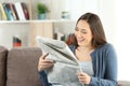 Happy lady reading a newspaper at home