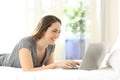 Happy lady using a laptop on the bed at home