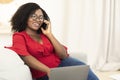 Happy lady using laptop calling her friend, sitting on couch Royalty Free Stock Photo