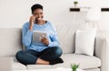 Happy lady using tablet calling her friend, sitting on couch Royalty Free Stock Photo