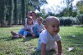 Happy, large family of five sitting on the lawn of a park, laughing as they watch the youngest one crawling away. Concept family, Royalty Free Stock Photo