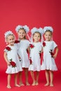 Happy large family of four sisters in embroidered white dresses on a plain red background in the studio Royalty Free Stock Photo