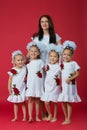 Happy large family of mother and four girls daughters in embroidered white dresses on a plain red background in the studio Royalty Free Stock Photo