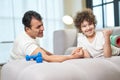 Strong guy. Happy latin boy looking satisfied after armwrestling together with his father at home, lying on the couch Royalty Free Stock Photo