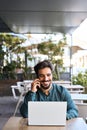 Happy Latin business man talking on mobile phone working on laptop outdoors. Royalty Free Stock Photo