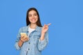 Happy Latin gen z teen girl using phone pointing aside isolated on blue. Royalty Free Stock Photo