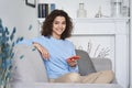 Happy latin teen girl holding cellphone sitting on sofa looking at camera. Royalty Free Stock Photo