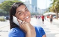 Happy latin woman with long dark hair at phone in city Royalty Free Stock Photo