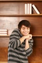 Happy latino-asian man in front of book shelf