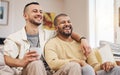 Happy, laugh and gay couple watching a movie on a sofa while relaxing with a cup of coffee. Love, bonding and young Royalty Free Stock Photo