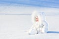 Happy laughing baby in snow on sunny winter day