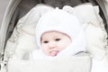 Happy laughing baby in a warm hat sitting in a stroller Royalty Free Stock Photo