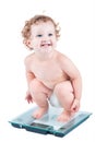 Happy laughing baby watching her weight on a scale Royalty Free Stock Photo