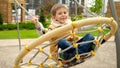 Happy laughing boy having fun swinging on the net swing on public playground. Active child, sports and development, kids playing Royalty Free Stock Photo