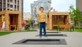 Happy laughing boy jumping high on trampoline at newly built public playground. Active child, sports and development, kids playing Royalty Free Stock Photo