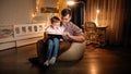 Happy laughing boy with young father sitting in bedroom at night and playing games on tablet computer. Concept of child Royalty Free Stock Photo