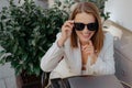 Happy laughing brown-haired woman freelancer,businesswoman, manager in sunglasses laughs at table in street cafe. Royalty Free Stock Photo