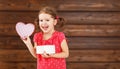 Happy laughing child girl with gift Valentine`s Day, wooden