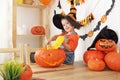 Happy laughing child girl in a witches hat cut a pumpkin for Hal Royalty Free Stock Photo