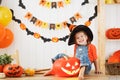 Happy laughing child girl in a witches hat cut a pumpkin for Hal Royalty Free Stock Photo