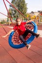 Happy laughing child swinging on a swing with arms outstretched at playground, vertical Royalty Free Stock Photo