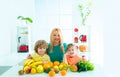 Happy laughing children and her beautiful young mother making fresh strawberry and other fruit juice for breakfast Royalty Free Stock Photo