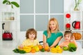 Happy laughing children and her beautiful young mother making fresh strawberry and other fruit juice for breakfast Royalty Free Stock Photo