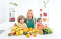 Happy laughing children and her beautiful young mother making fresh strawberry and other fruit juice in kitchen. Happy Royalty Free Stock Photo