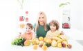 Happy laughing children and her beautiful young mother making fresh strawberry and other fruit juice in kitchen. Happy Royalty Free Stock Photo