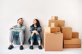 Happy laughing couple sitting on floor in their new home surrounded by cardboard boxes Royalty Free Stock Photo